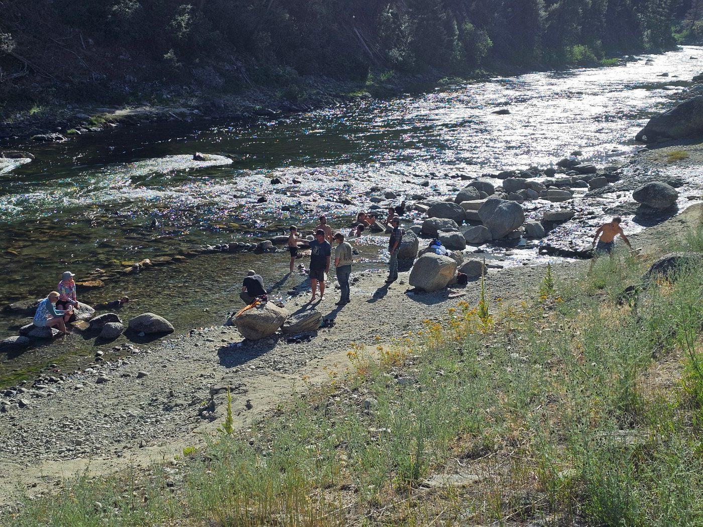 Riders taking a break beside a wide whitewater river in central Idaho
